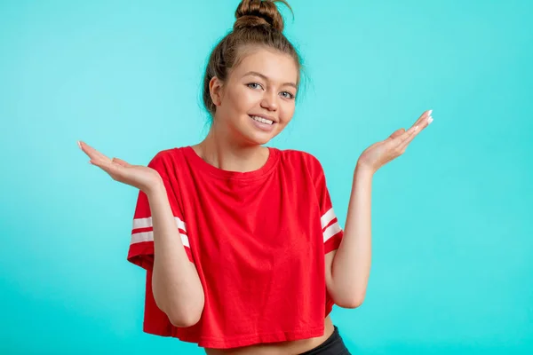 Alegre joven mujer en rojo deportivo camiseta encogiéndose de hombros —  Fotos de Stock