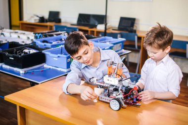 İki kardeş okul robotik sınıfında oyuncak robotla oynuyorlar..