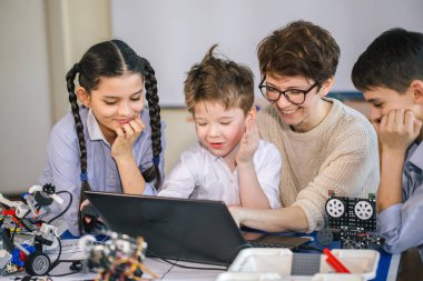 Mutlu çocuklar ders dışı derslerde dizüstü bilgisayar kullanarak programlama öğrenirler.