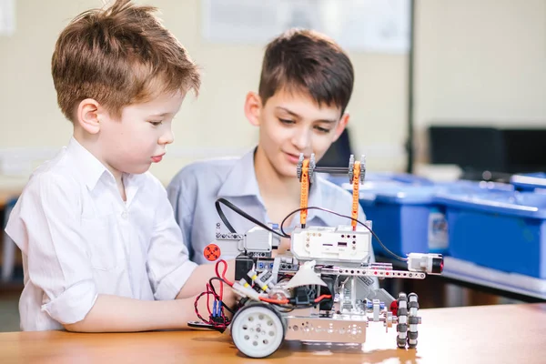 Dois irmãos crianças brincando com robô brinquedo na escola aula de robótica, indoor . — Fotografia de Stock