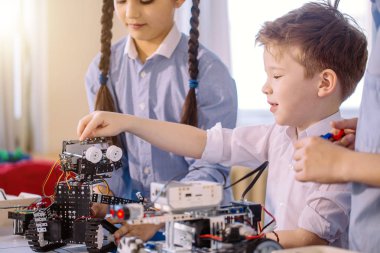 Robot sergisini ziyaret ederken çocuklar elektrikli robotla oynuyorlar