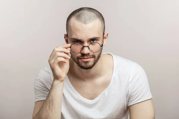 Brutální vousatý muž nosí kulaté brýle, oblečená ležérně, — Stock fotografie