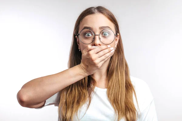 Ung förvånad kaukasisk kvinna stänga munnen med handen på vit bakgrund — Stockfoto