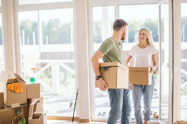 Pareja feliz llevando cajas de cartón en un nuevo hogar en el día de mudanza —  Fotos de Stock