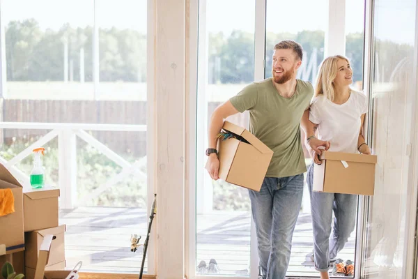 Pareja feliz llevando cajas de cartón en un nuevo hogar en el día de mudanza — Foto de Stock