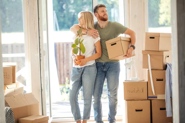 Pareja feliz llevando cajas de cartón en un nuevo hogar en el día de mudanza — Foto de Stock