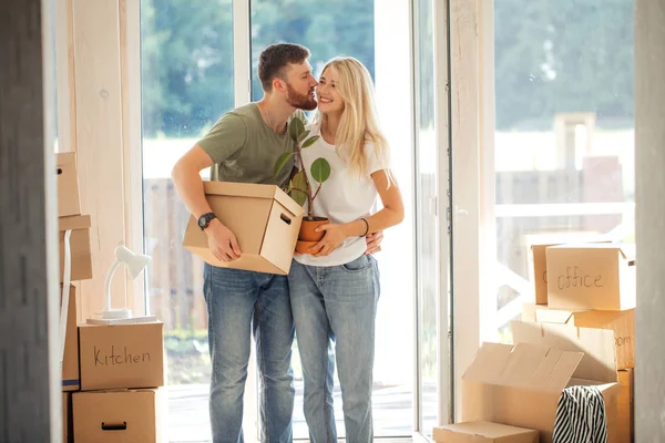 Pareja feliz llevando cajas de cartón en un nuevo hogar en el día de mudanza — Foto de Stock