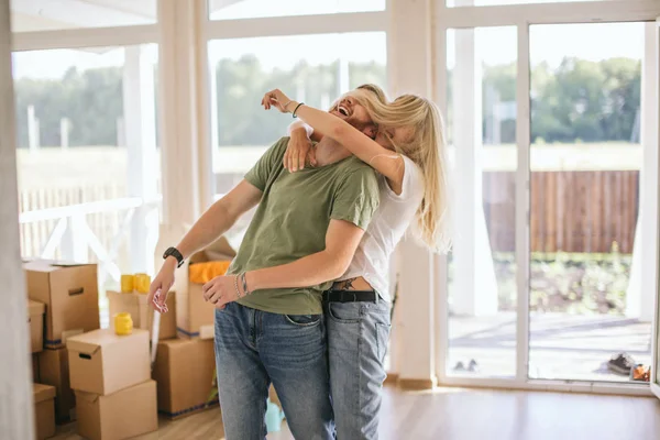 Couple heureux étreignant dans la chambre avec des boîtes mobiles à la nouvelle maison — Photo