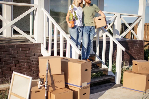สามีและภรรยายืนอยู่หน้าบ้านซื้อใหม่พร้อมกล่อง — ภาพถ่ายสต็อก