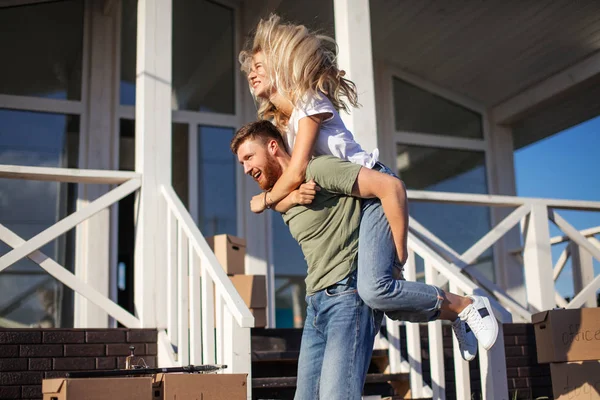Пара наслаждается рядом с новой квартирой и муж на спине жены снаружи — стоковое фото