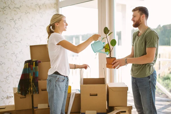 Pareja desempacar cajas en un nuevo hogar. Mujer dando flor a su marido — Foto de Stock