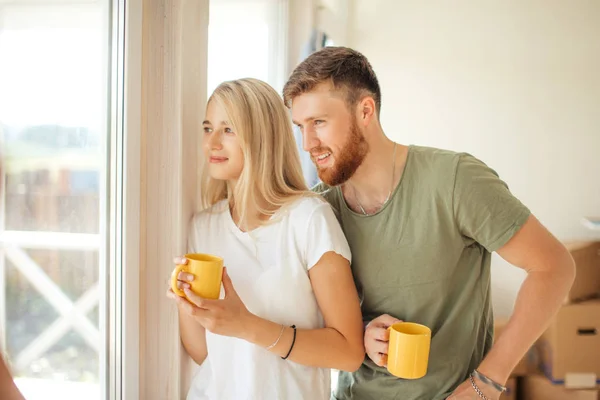 Hombre y mujer bebiendo té cerca de la ventana. Comprado casa nueva o apartamento — Foto de Stock