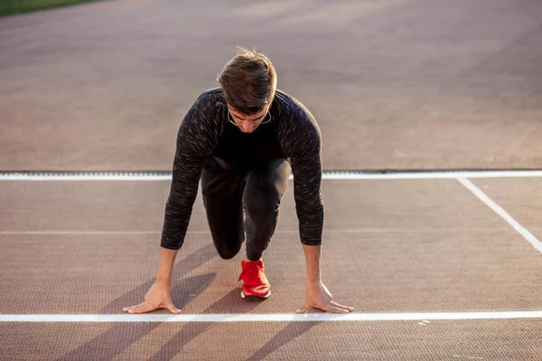 Athlète en position de départ sur piste de course. Runner pratiquant la course dans le stade hippodrome — Photo