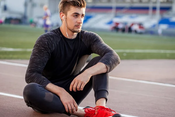 Es hora de descansar. hombre descansando después de correr en pista en el estadio —  Fotos de Stock