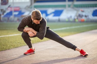 Adam stadyumdaki yarış pistinde koşmadan önce vücudu gerer.
