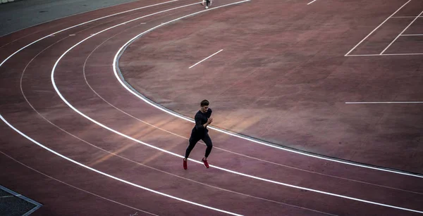 Top-Ansicht Athlet läuft auf Laufstrecke. Läufer sprintet auf roter Laufbahn im Stadion — Stockfoto