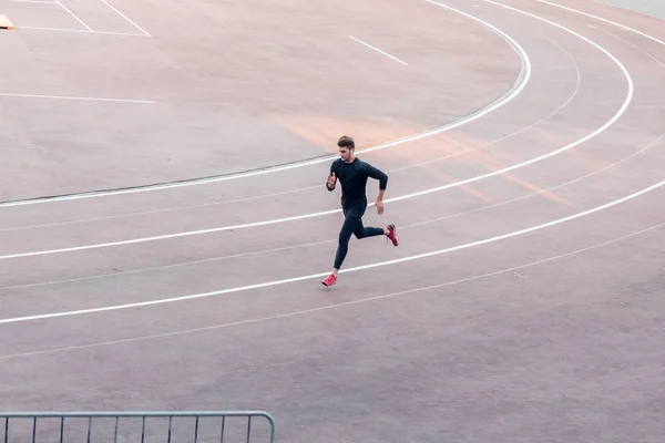 Vista superior Atleta corriendo en pista de atletismo. Corredor corriendo en pista roja en el estadio —  Fotos de Stock