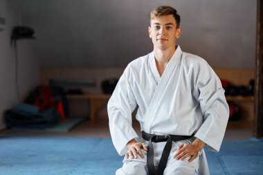 Kimono erkekte karate dövüş sanatları salonunda yere çök oturur