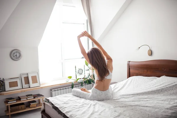 Mulher meditando em sua cama, visão traseira — Fotografia de Stock