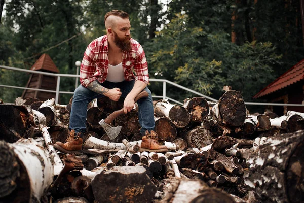 Man sitting on firewoods. Woodcutter with axe resting after work — Stock Photo, Image