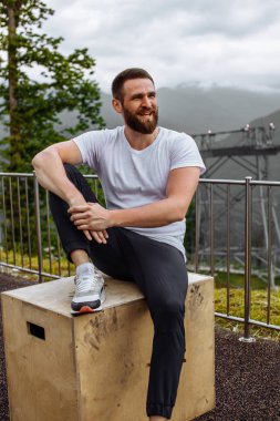 Yakışıklı kaslı adam tepeden dağlara bakıyor..