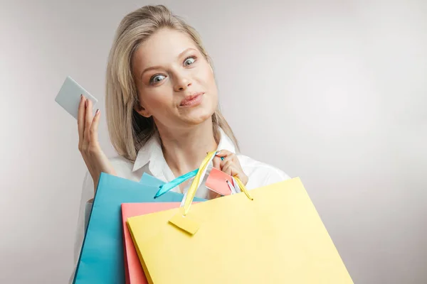 Jeune femme blonde heureuse avec des sacs à provisions de différentes couleurs — Photo