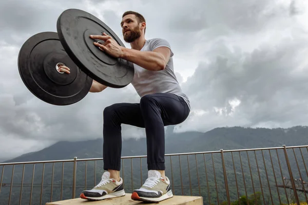 Fuerte atleta masculino haciendo saltos de caja con dos placas al aire libre en la cima de la montaña. — Foto de Stock