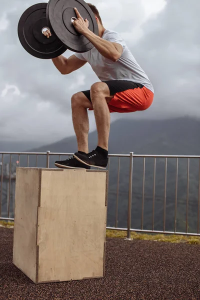 Fuerte atleta masculino haciendo saltos de caja con dos placas al aire libre en la cima de la montaña. — Foto de Stock