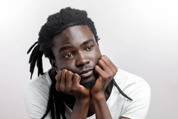 Pensando o sognando uomo africano con dreadlocks su sfondo bianco — Foto Stock