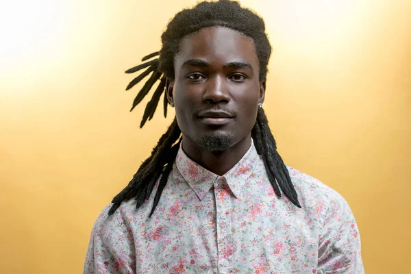 年轻英俊的非洲男子，身穿黄色背景的花衬衫 — 图库照片