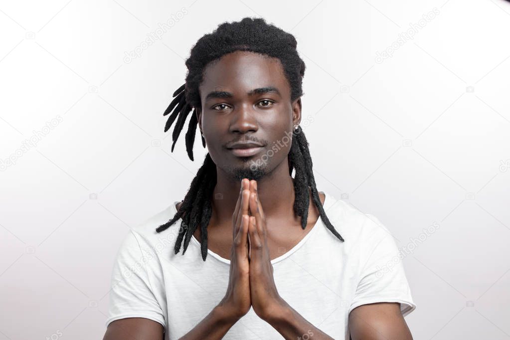 Close up of black man with dreadlocks praying on white background
