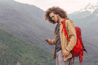 Yürüyüş sırasında dinlenen bir adam oturur ve telefonunu karıştırır.