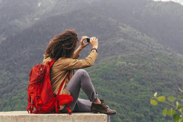 Man neemt foto met mobiele telefoon zittend op rots — Stockfoto