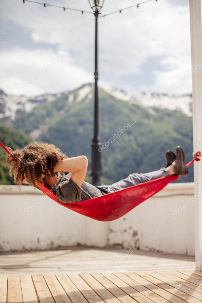 happy man relaxing lying in hammock on top of mountain. Summer vacation travel lifestyle concept