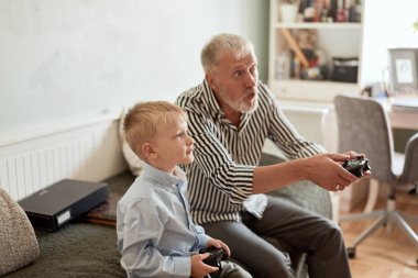 Dedem ve torunum bilgisayar başında joystick ile oyun oynuyorlar.