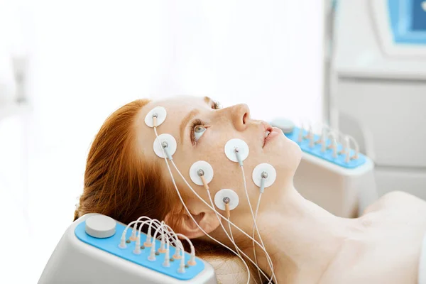 Giovane donna con elettrodi sul viso, riceve stimolazione elettrica. — Foto Stock