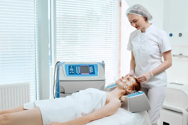 Žena s elektrodami na tváři, dostává elektrickou stimulaci na kůži. — Stock fotografie