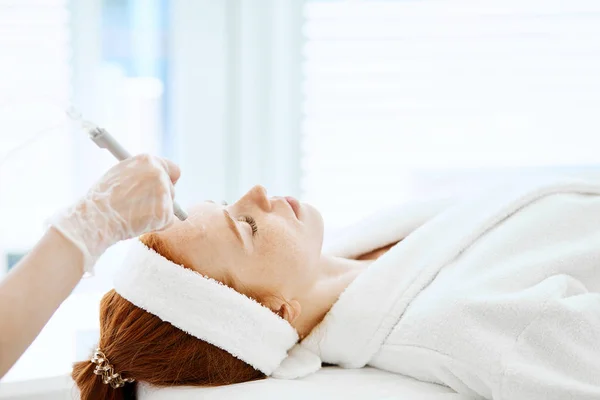 Een vrouw die gezichtsbehandeling krijgt in een schoonheidscentrum. Vloeibare peeling van het gelaat — Stockfoto