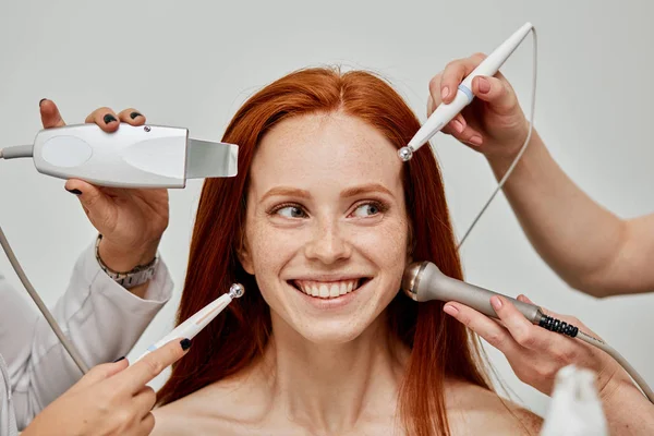 Konceptuell bild av kvinnligt känslomässigt ansikte och kosmetolog händer med enheter — Stockfoto