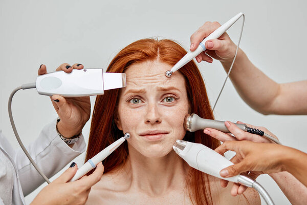 Conceptual image of female emotional face and cosmetologist hands with devices