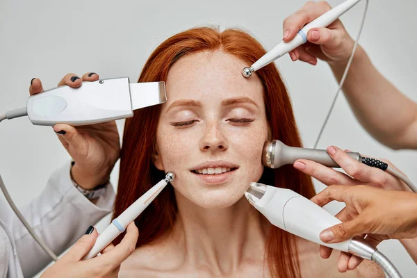 Концептуальное изображение женского эмоционального лица и рук косметолога с помощью устройств — стоковое фото