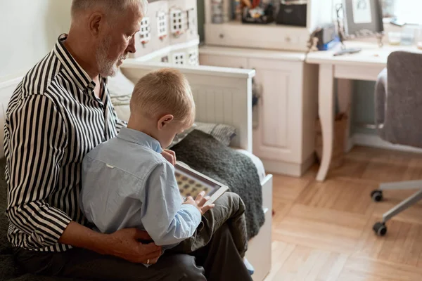 Dědeček a vnuk pomocí digitálního tabletu při sezení na gauči — Stock fotografie