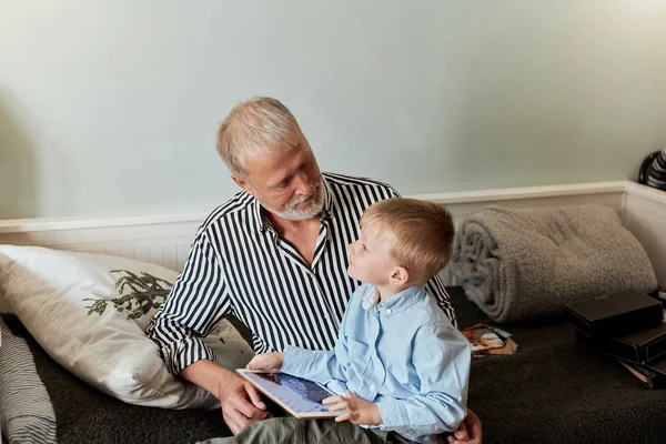 Παππού και εγγονός χρησιμοποιώντας ψηφιακή ταμπλέτα, ενώ κάθεται στον καναπέ — Φωτογραφία Αρχείου