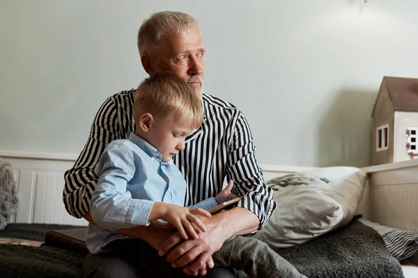 Abuelo y nieto usando tableta digital mientras están sentados en el sofá —  Fotos de Stock