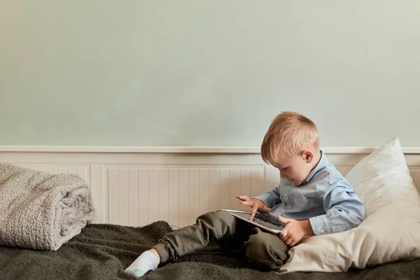 Niño con tableta digital sentado en el sofá, en la sala de estar — Foto de Stock