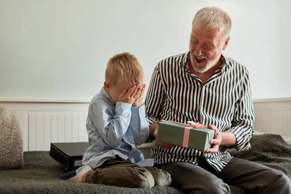 Generación. abuelo y nieto con caja de regalo sentado en el sofá en casa — Foto de Stock