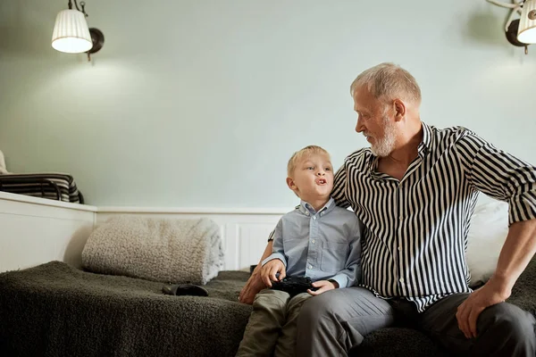 Generace. dědeček a vnuk s dárkovou krabicí sedí doma na gauči — Stock fotografie