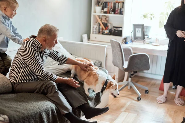 Abuelo y nieto con perro sentado en el sofá en la habitación — Foto de Stock