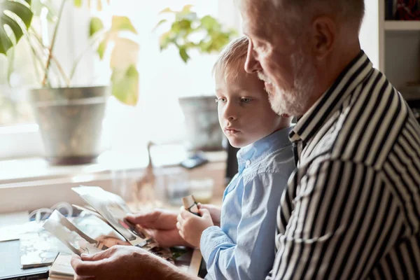 Abuelo y nieto en el sofá en casa. Abuelo y niños viendo fotos viejas —  Fotos de Stock