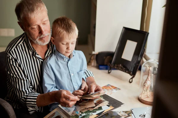 Morfar och sonson på soffan hemma. Morfar och barn tittar på gamla foton — Stockfoto